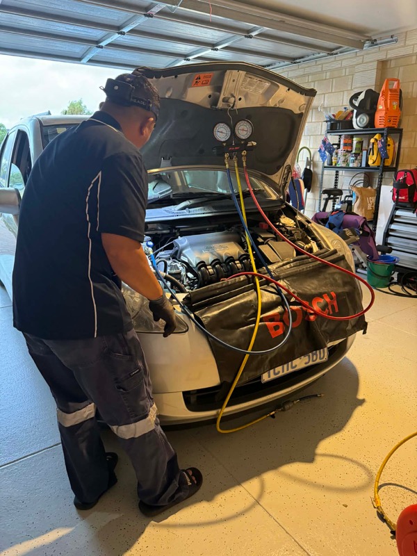 Technician servicing a vehicle air conditioning system in a workshop