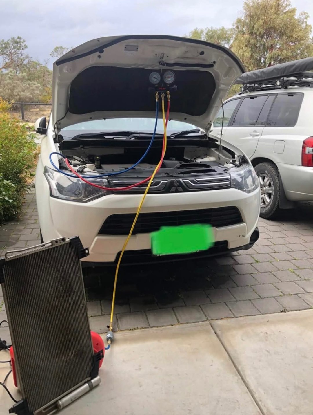 White Mitsubishi Outlander undergoing air conditioning service with its bonnet open