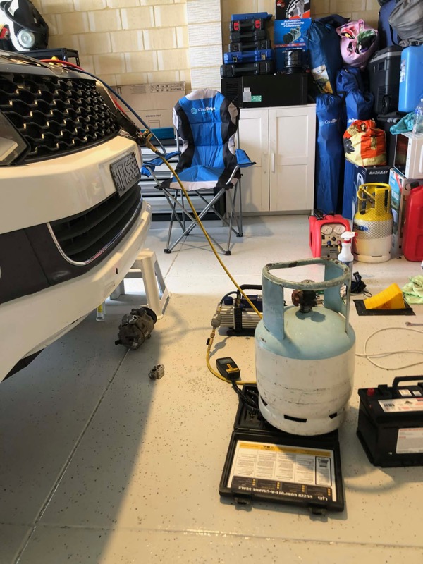 White Toyota LandCruiser undergoing air conditioning service with equipment beside it