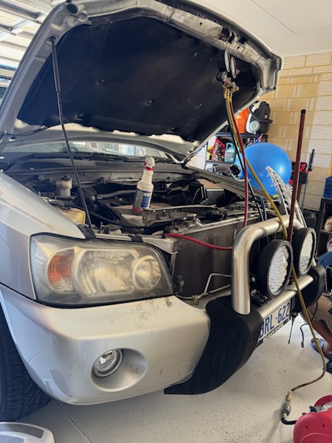 Silver four-wheel drive with air conditioning service gauges connected under the open bonnet
