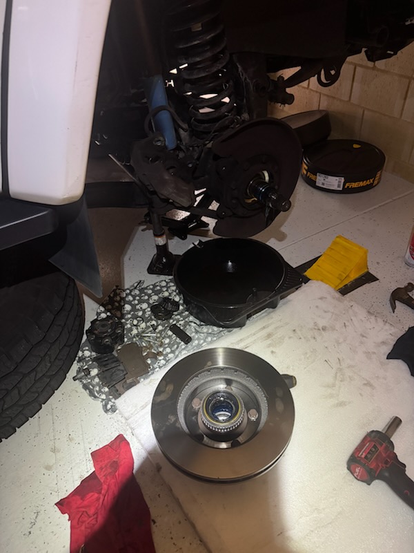 Brake disc and hub assembly beside a vehicle during mechanical work